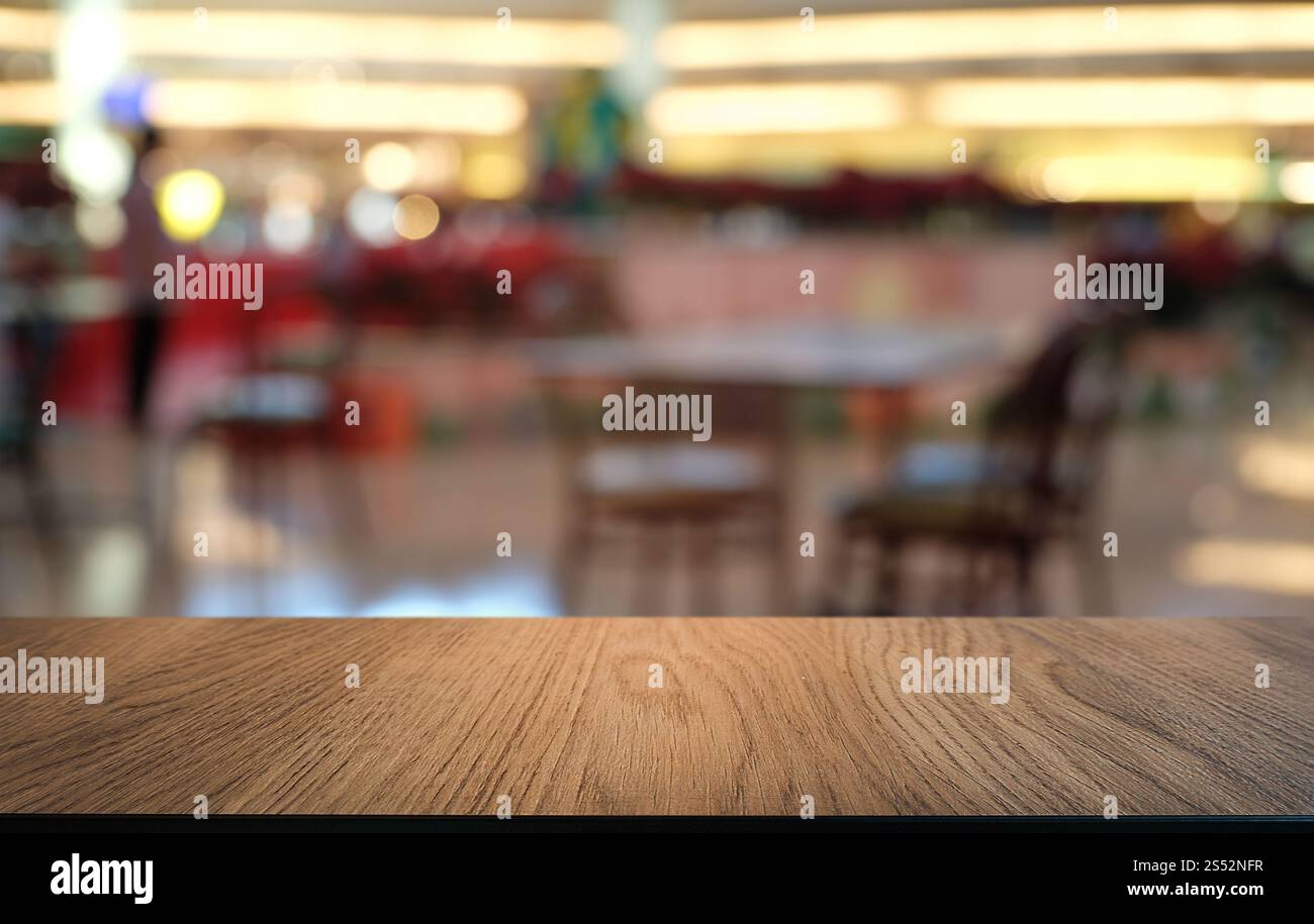 Tavolo vuoto di legno scuro davanti allo sfondo bokeh astratto e sfocato del ristorante. può essere utilizzato per la visualizzazione o il montaggio dei prodotti. Mock-up per Foto Stock