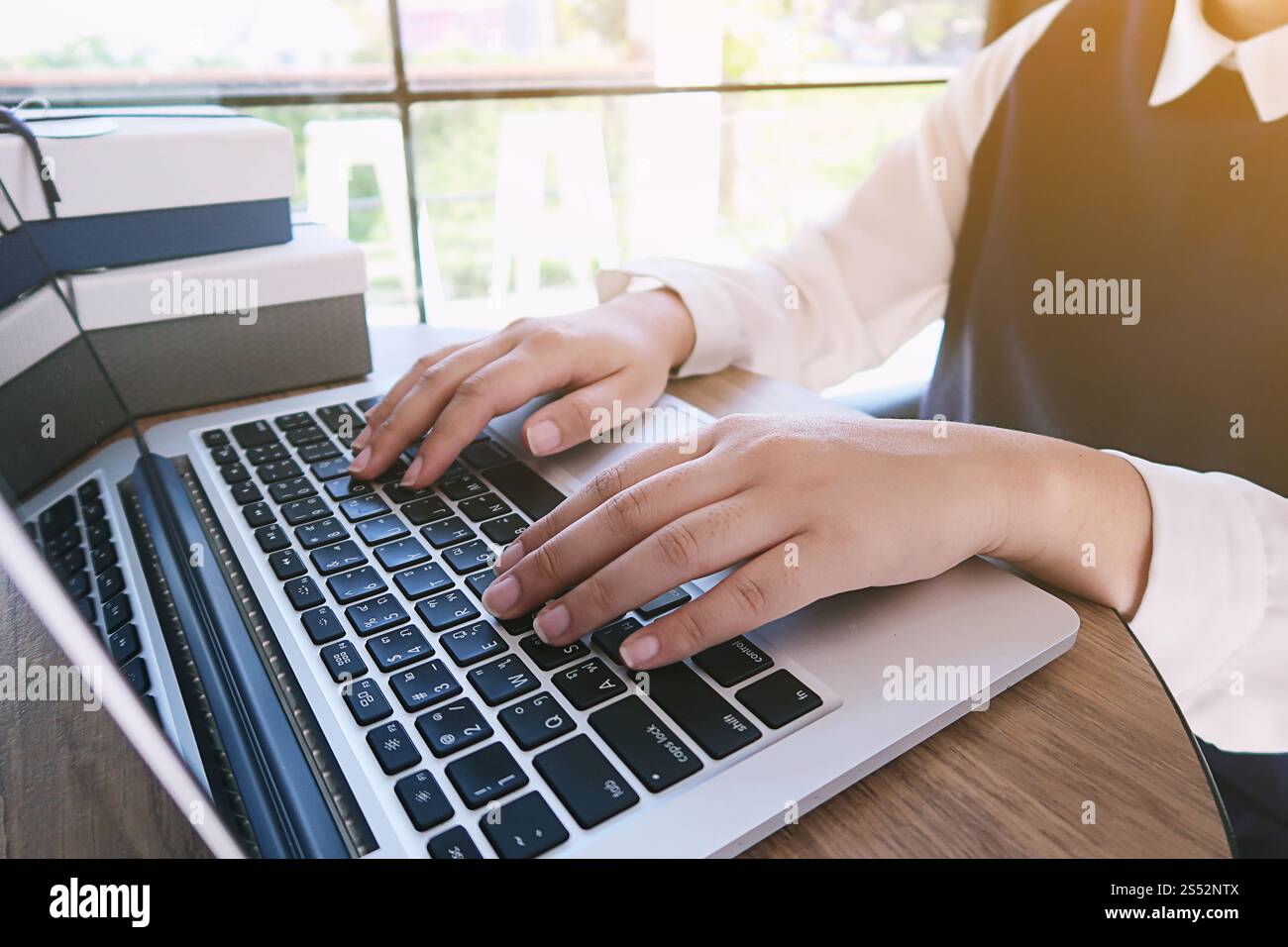 Uomo che lavora utilizzando un computer portatile su un tavolo di legno. Digitazione con le mani su una tastiera Foto Stock