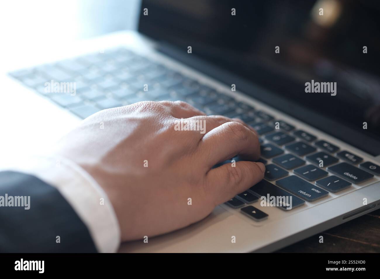 Uomo che lavora utilizzando un computer portatile su un tavolo di legno. Digitazione con le mani su una tastiera Foto Stock