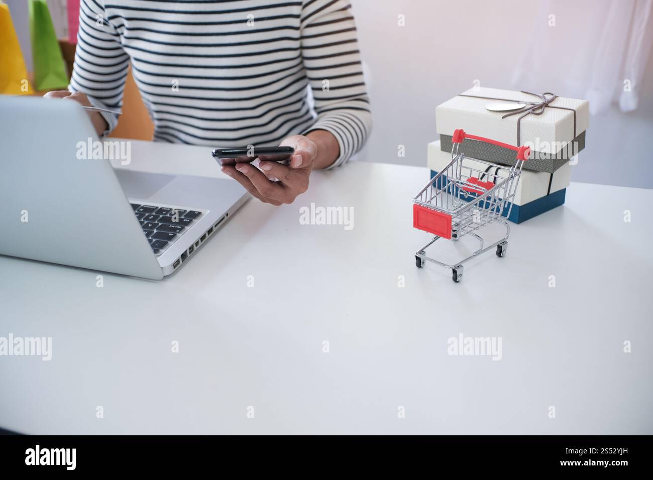 Donna e piccolo carrello con il computer portatile per Internet shopping on line concept Foto Stock