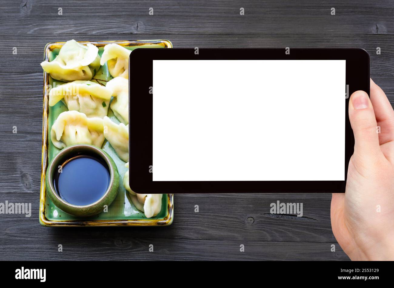 Concetto di viaggio - tourist fotografie di cucina Cinese piatto di gnocchi con tre riempimenti (gamberetti, uovo, verdi) sulla piastra su smartphone con vuoto Foto Stock