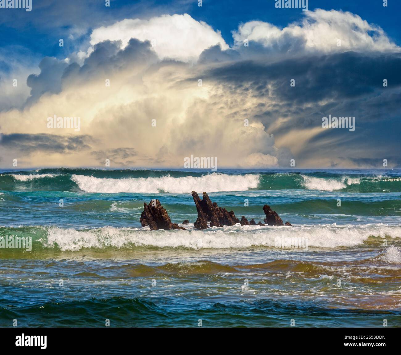 Mare onde da surf e piccole rocce in centro. Seascape vista dalla spiaggia. Foto Stock