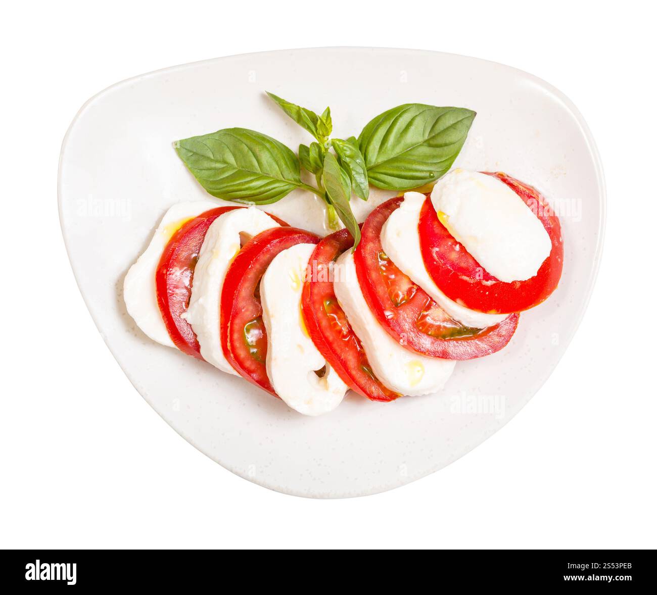 insalata caprese di cucina italiana - vista dall'alto della mozzarella affettata e del pomodoro con ramoscello di basilico condito con olio d'oliva sul piatto Foto Stock