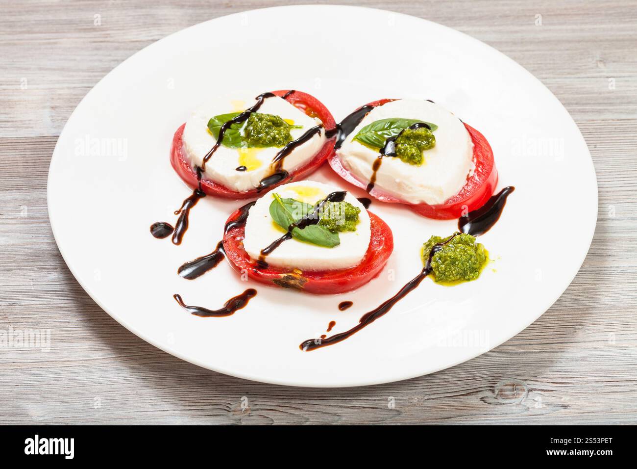 insalata caprese della cucina italiana - faraglioni di mozzarella affettata, pomodoro, foglie di basilico condite con olio d'oliva, aceto balsamico Foto Stock