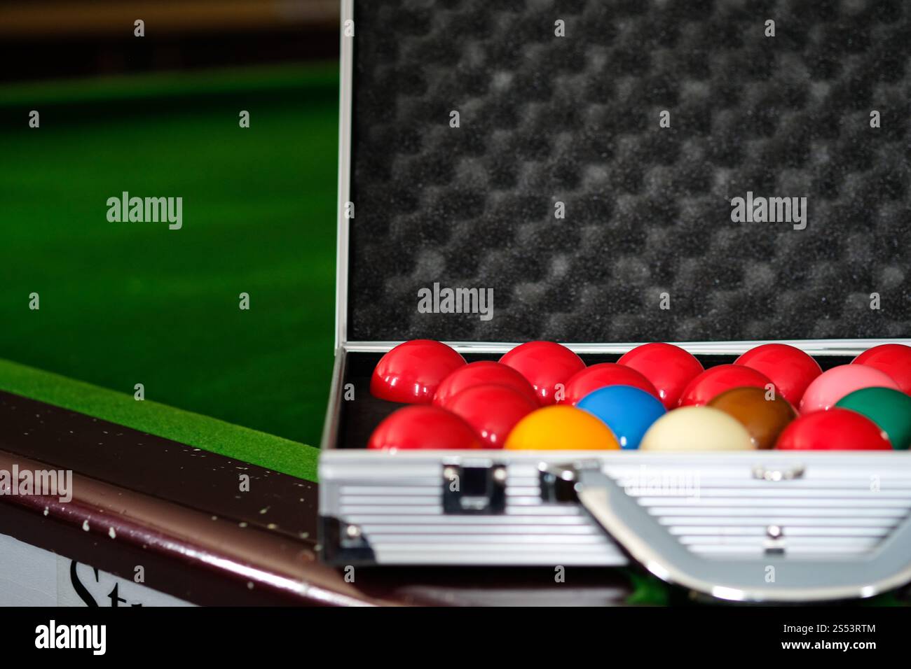 Mans mano e braccio cue giocano a biliardo o si preparano a sparare palle da biliardo su un tavolo da biliardo verde. Palline da biliardo colorate sul fregio verde Foto Stock