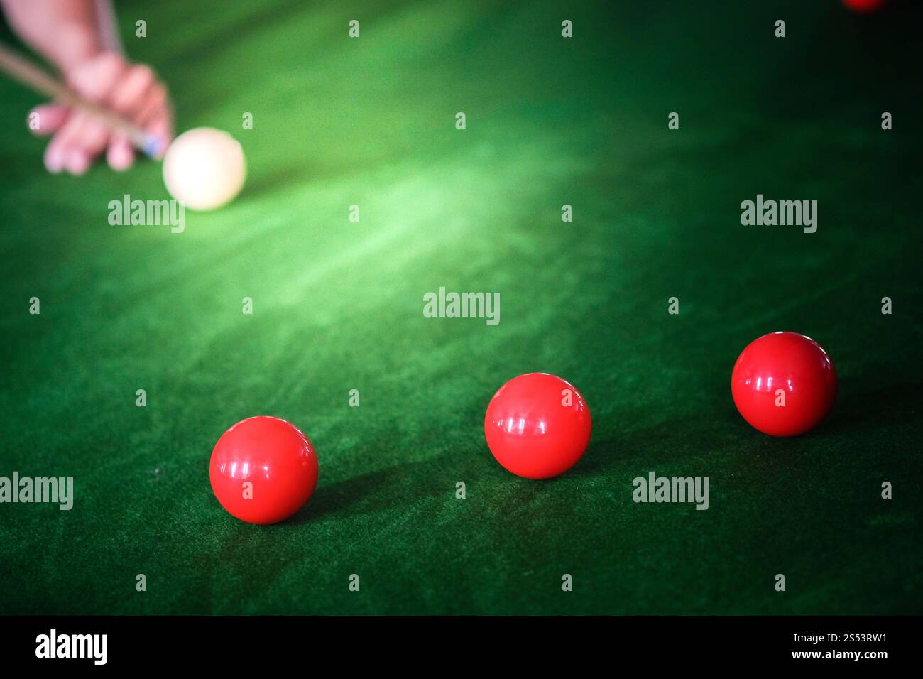 Mans mano e braccio cue giocano a biliardo o si preparano a sparare palle da biliardo su un tavolo da biliardo verde. Palline da biliardo colorate sul fregio verde Foto Stock