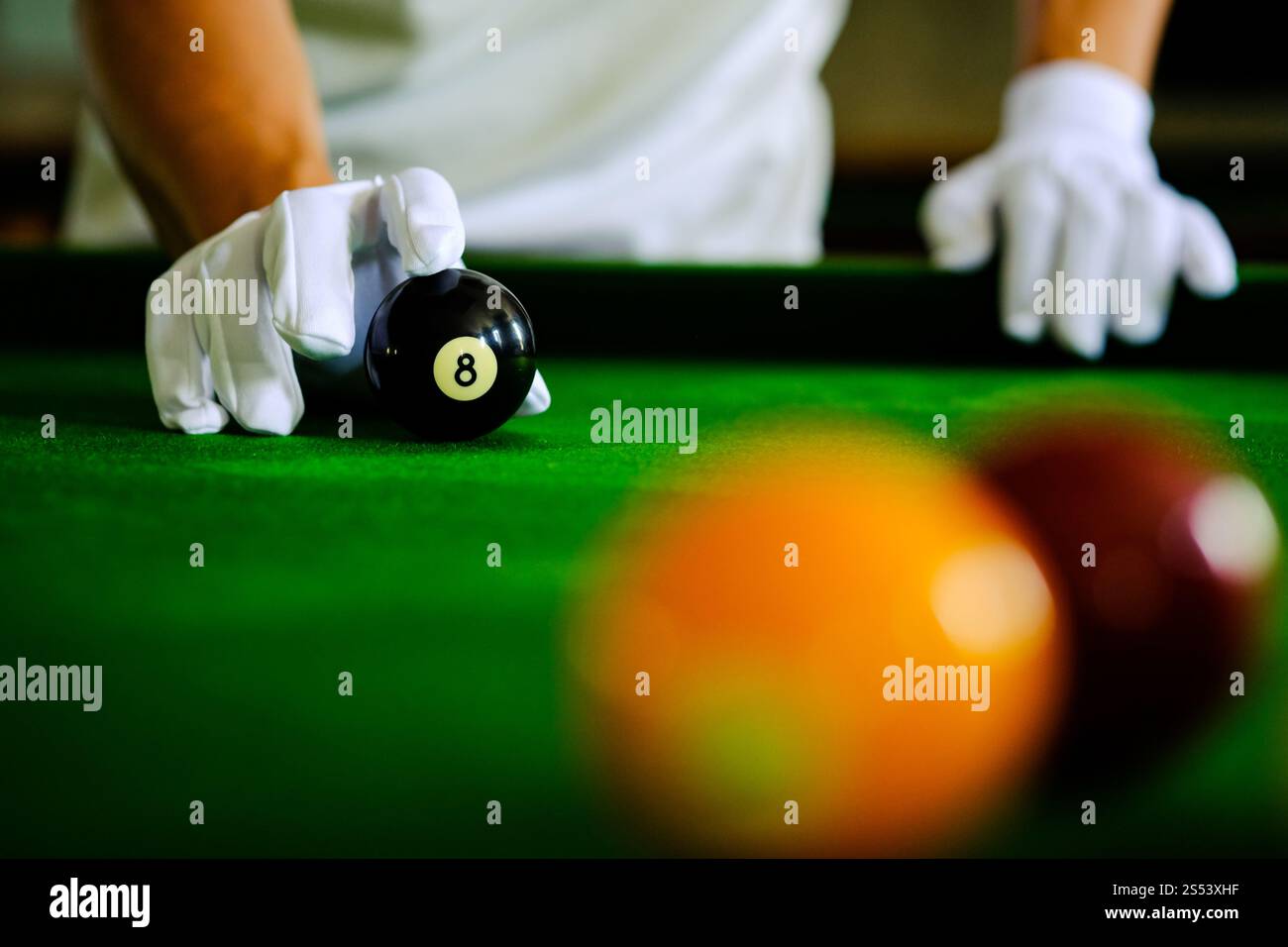 Mans mano e braccio cue giocano a biliardo o si preparano a sparare palle da biliardo su un tavolo da biliardo verde. Palline da biliardo colorate sul fregio verde Foto Stock