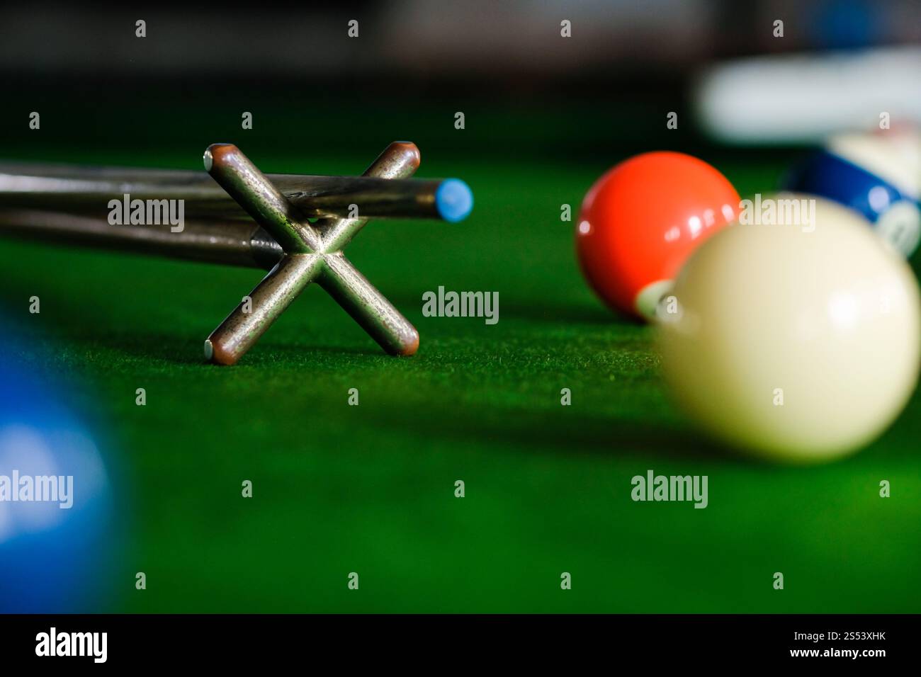 Mans mano e braccio cue giocano a biliardo o si preparano a sparare palle da biliardo su un tavolo da biliardo verde. Palline da biliardo colorate sul fregio verde Foto Stock