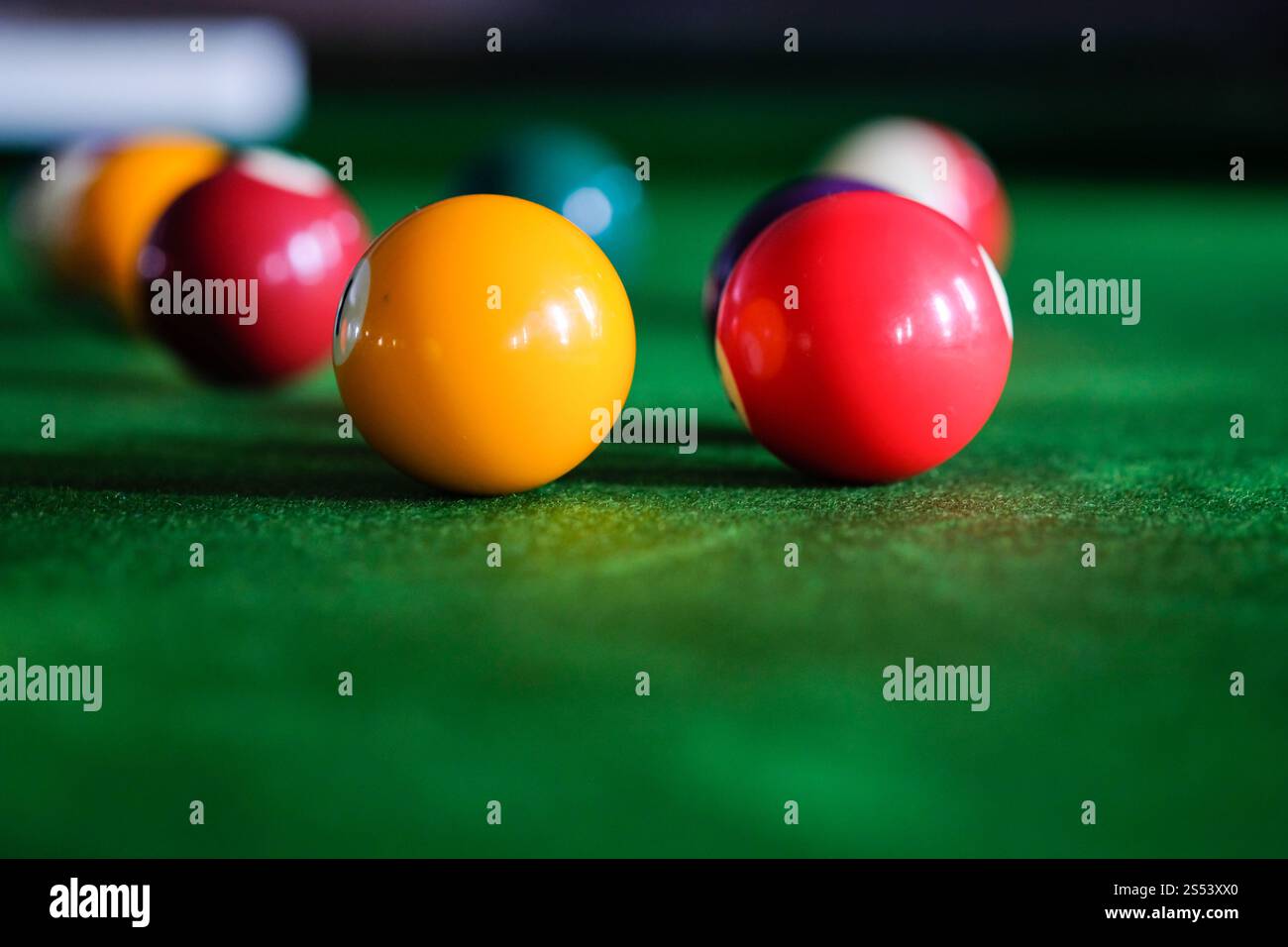 Mans mano e braccio cue giocano a biliardo o si preparano a sparare palle da biliardo su un tavolo da biliardo verde. Palline da biliardo colorate sul fregio verde Foto Stock