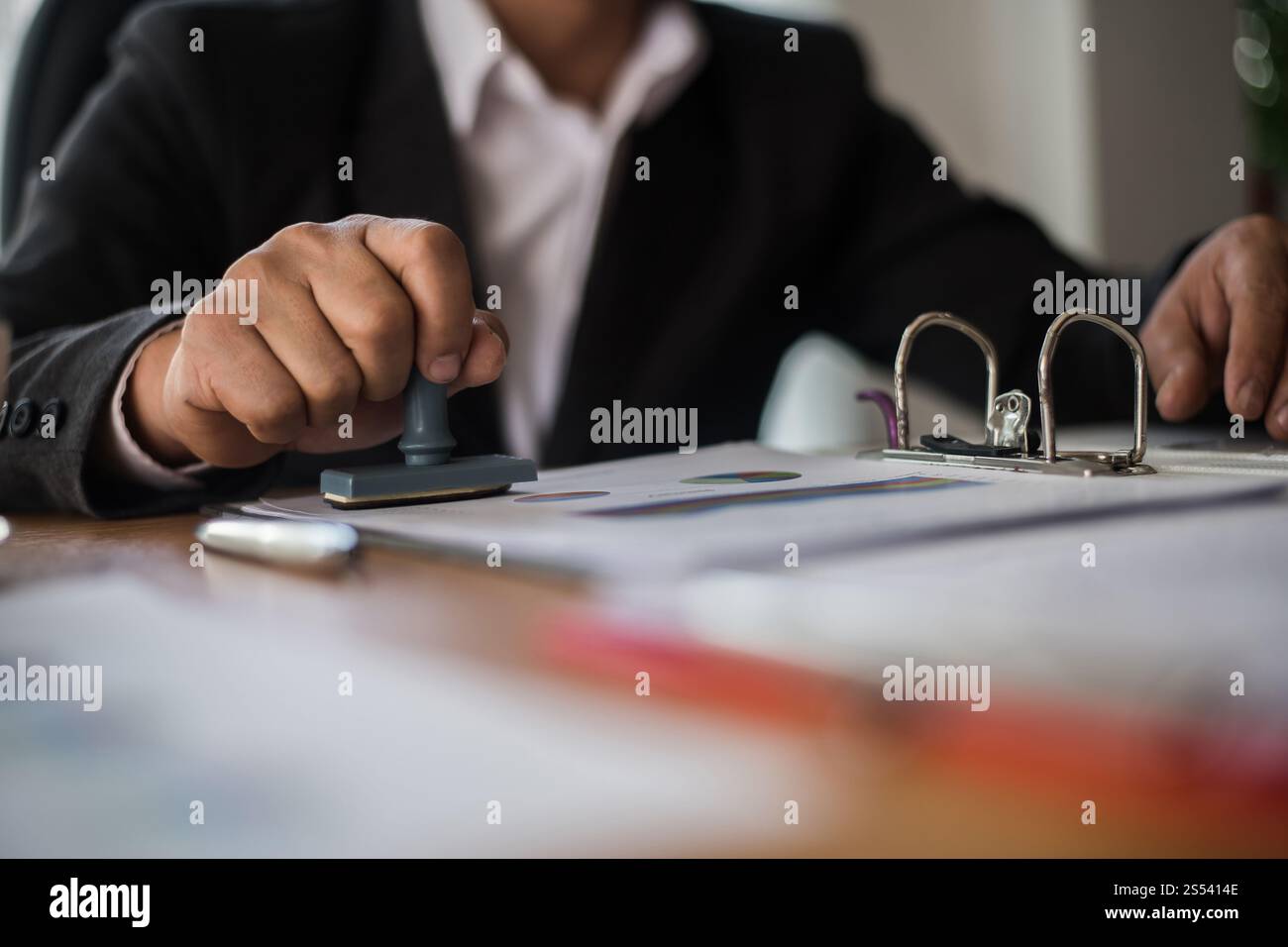 Manuale d'affari che preme il timbro di gomma approvato sul documento di contratto di affari Foto Stock