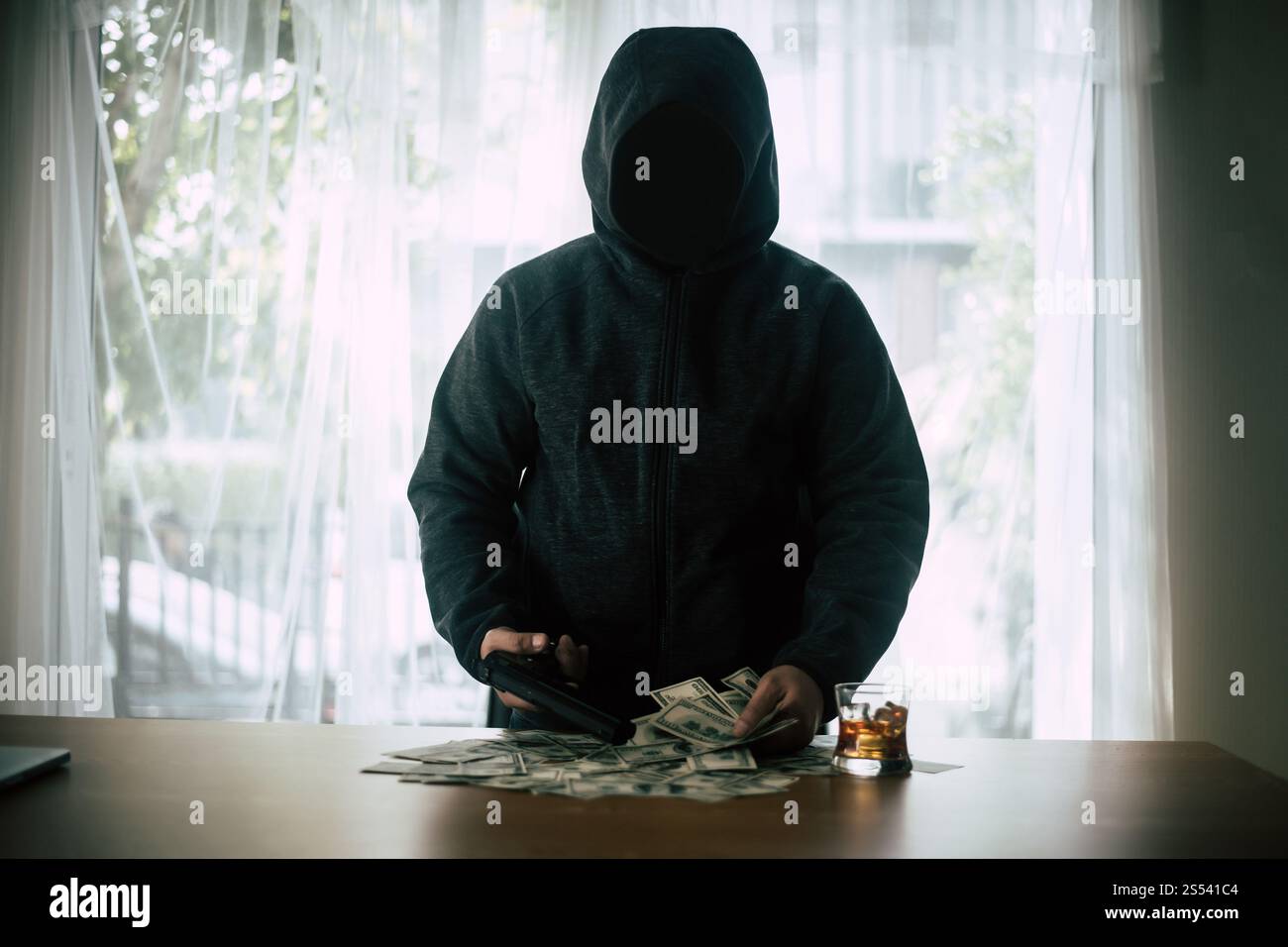 Tiro con la pistola criminale con cappuccio con dollaro Foto Stock