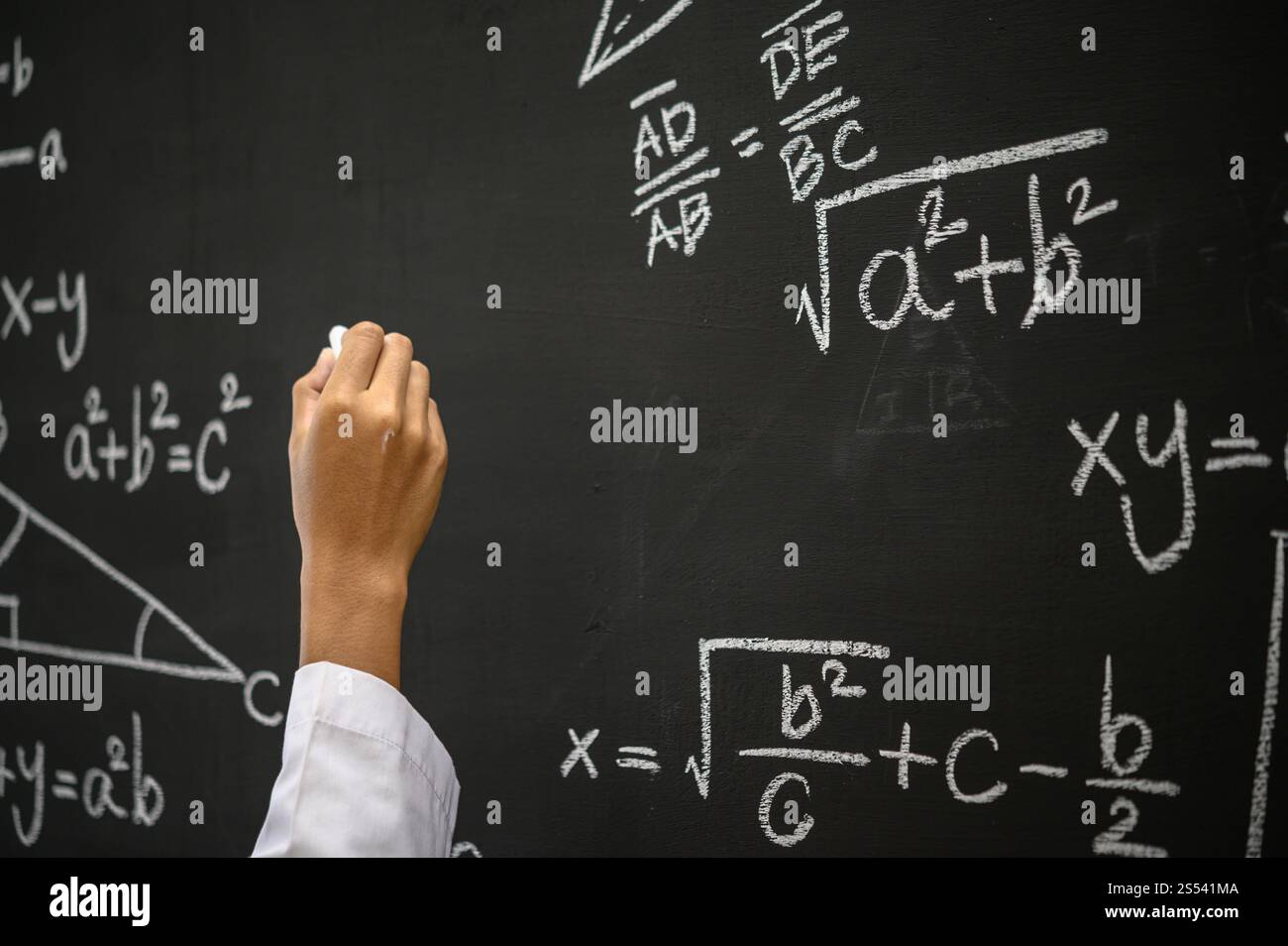 La mano che scrive la formula con gesso bianco sulla lavagna Foto Stock