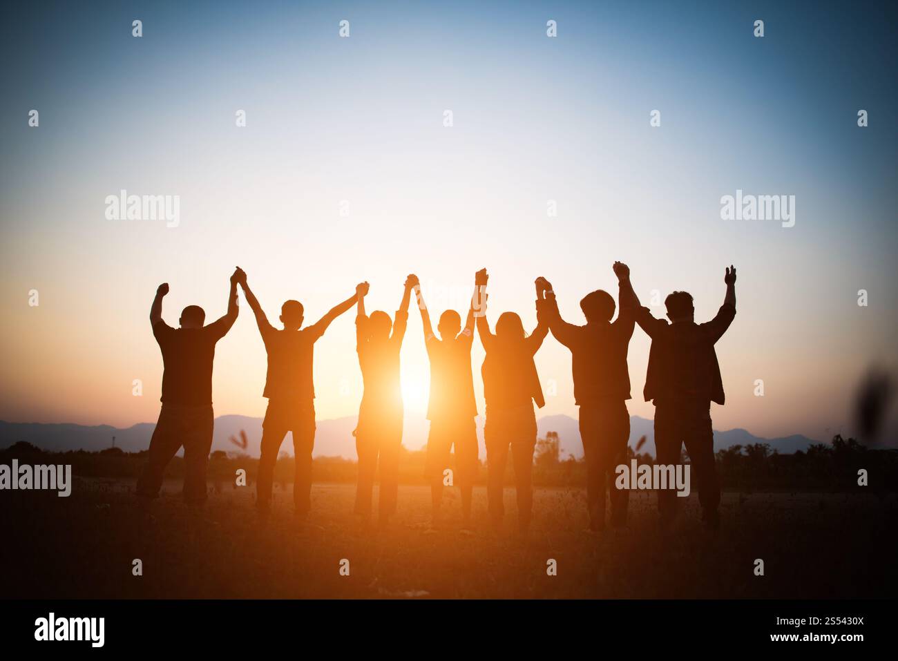 Silhouette di un team di uomini d'affari felice che fa le mani alte sopra la testa nel cielo del tramonto sfondo del tempo serale per il concetto di lavoro di squadra e la libertà Foto Stock