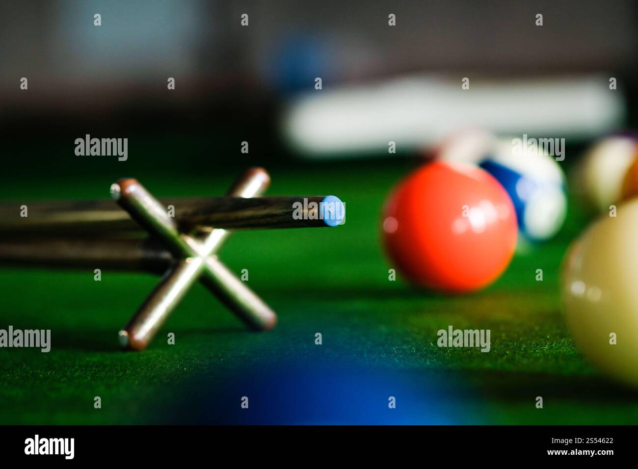 Mans mano e braccio cue giocano a biliardo o si preparano a sparare palle da biliardo su un tavolo da biliardo verde. Palline da biliardo colorate sul fregio verde Foto Stock