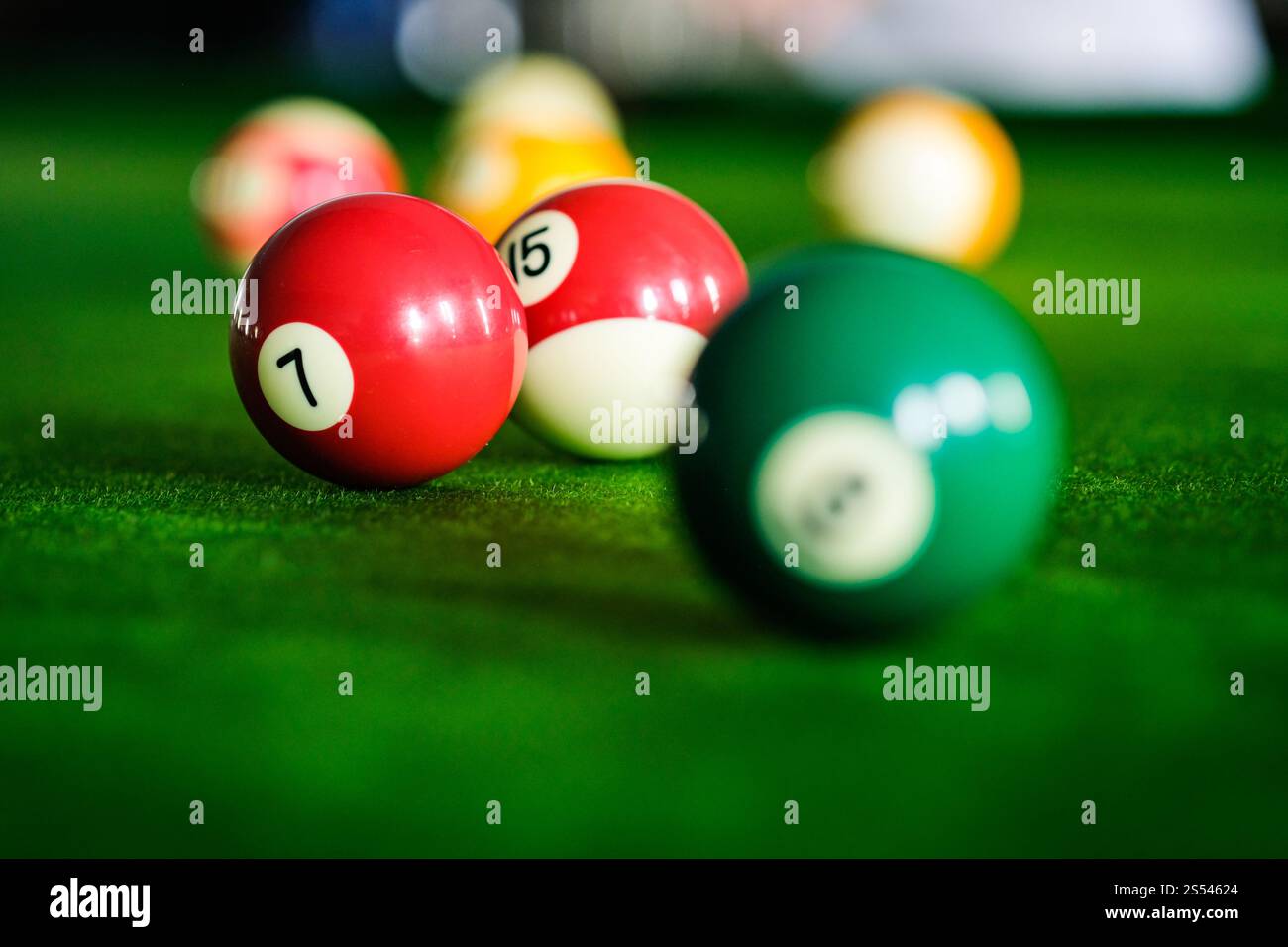Mans mano e braccio cue giocano a biliardo o si preparano a sparare palle da biliardo su un tavolo da biliardo verde. Palline da biliardo colorate sul fregio verde Foto Stock