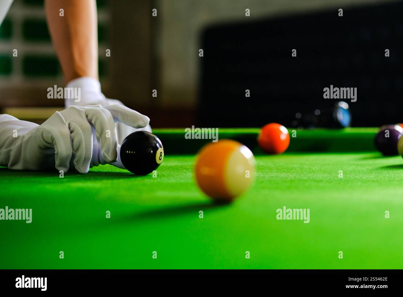 Mans mano e braccio cue giocano a biliardo o si preparano a sparare palle da biliardo su un tavolo da biliardo verde. Palline da biliardo colorate sul fregio verde Foto Stock