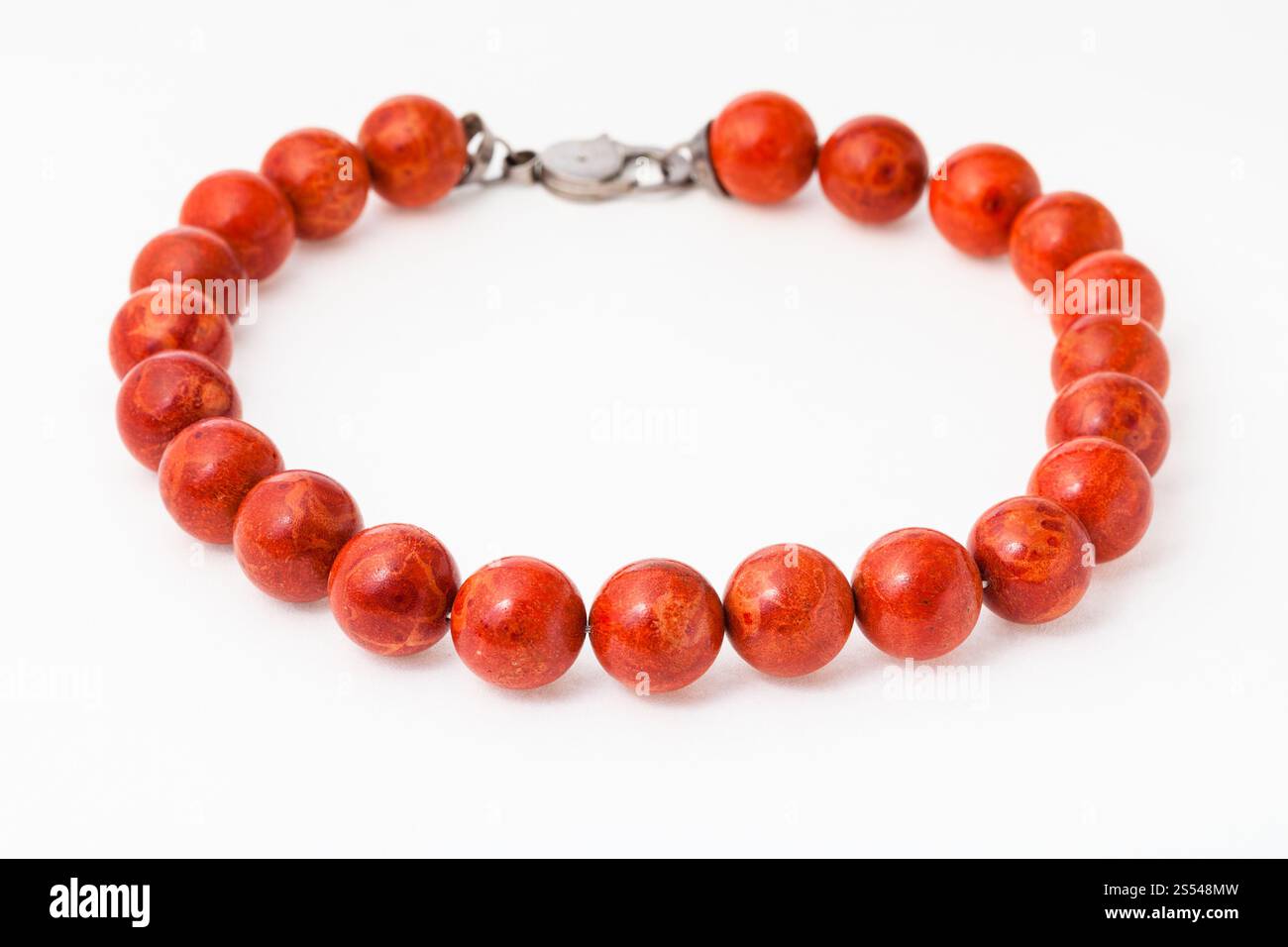 Collana da naturale lucidato rosso corallo sfere sul libro bianco sullo sfondo Foto Stock