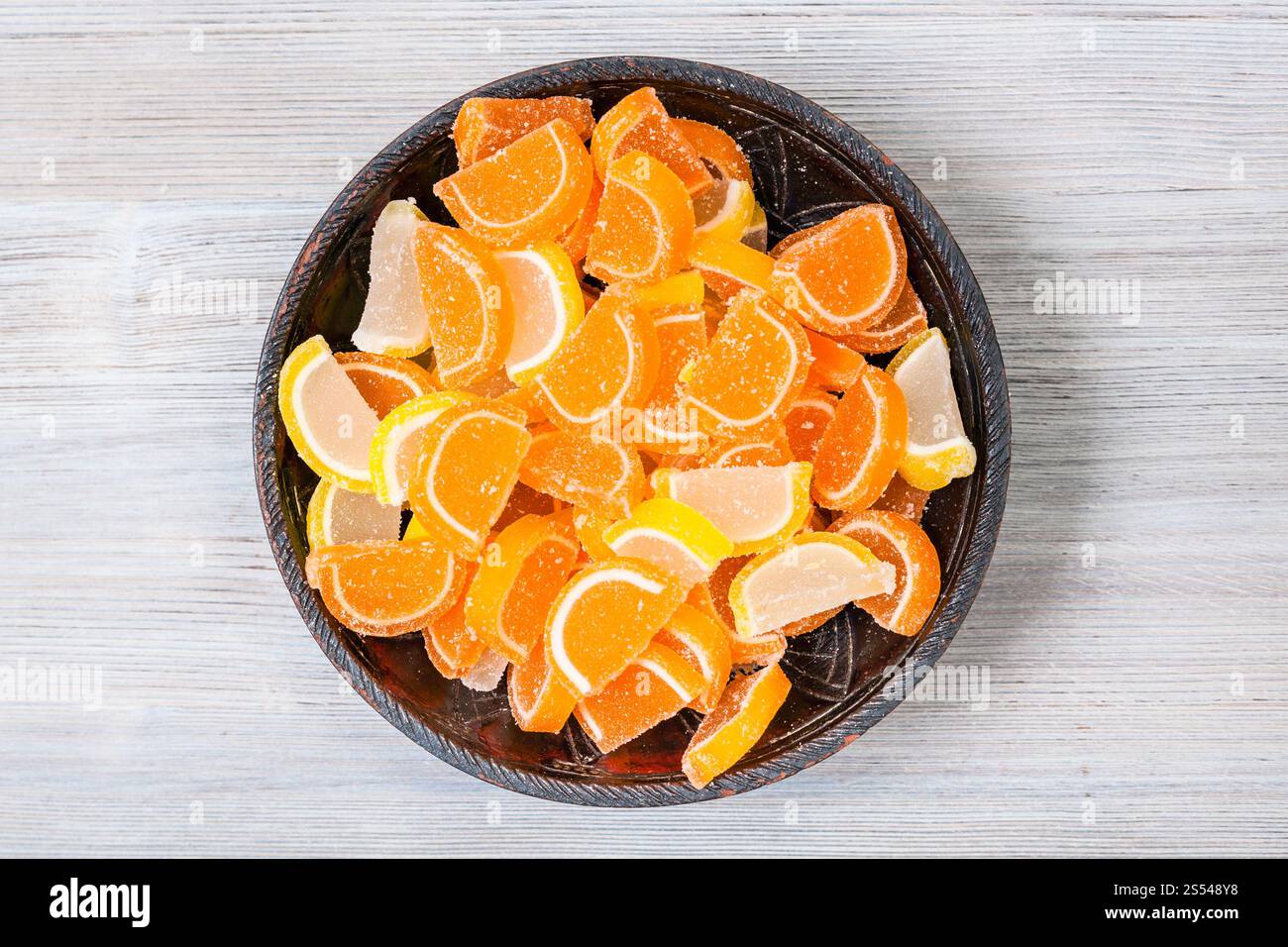 Vista superiore del dolce zucchero e limone Marmellata di arance fette nel recipiente di ceramica su grigio pannello di legno Foto Stock