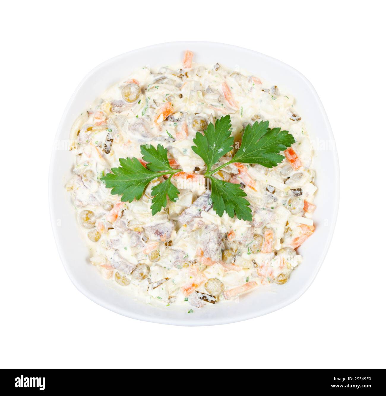 Vista dall'alto della porzione di insalata russa Olivier decorata con foglie di prezzemolo in ciotola bianca isolata su sfondo bianco. Porzione di insalata Olivier con Foto Stock