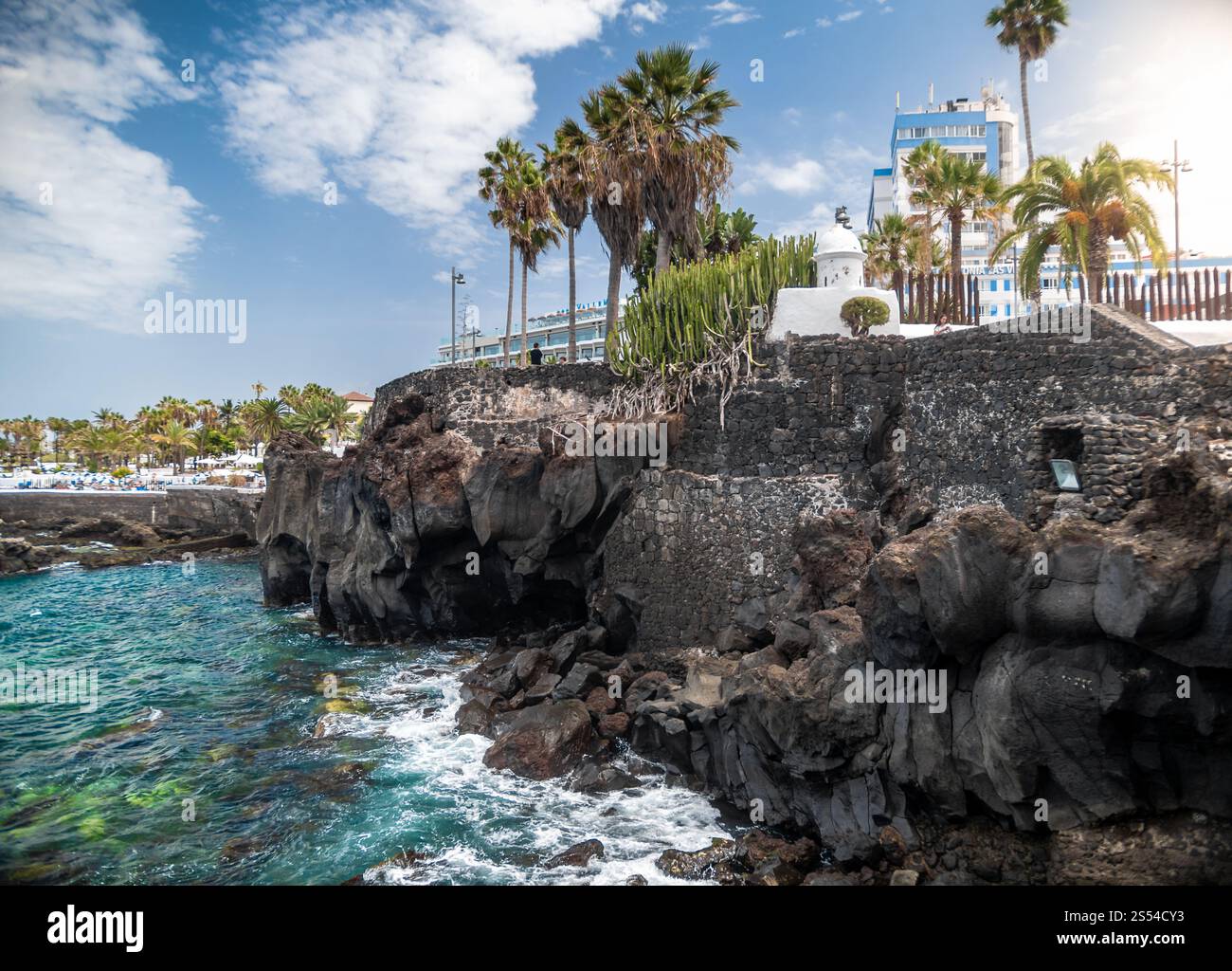 Foto incredibili su palme verdi e edificio moderno in cima alle alte scogliere vulcaniche nella laguna oceanica. Splendida vista su palme verdi e moderno Foto Stock
