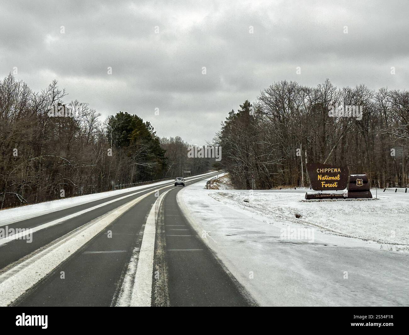 CASS CO, Minnesota - 24 marzo 2024: Autostrada invernale con neve e cartello per la foresta nazionale di Chippewa. Foto Stock