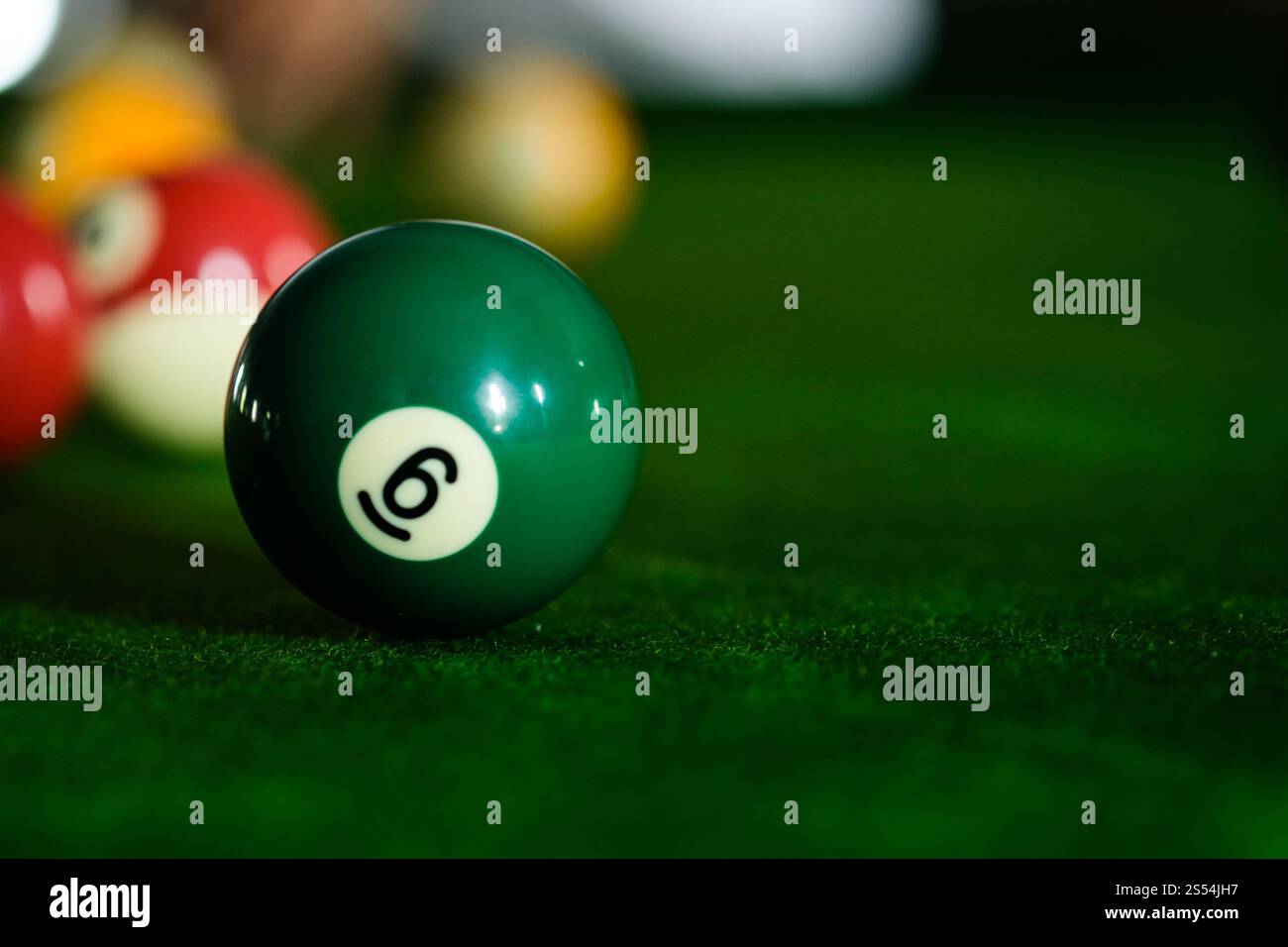 Mans mano e braccio cue giocano a biliardo o si preparano a sparare palle da biliardo su un tavolo da biliardo verde. Palline da biliardo colorate sul fregio verde Foto Stock