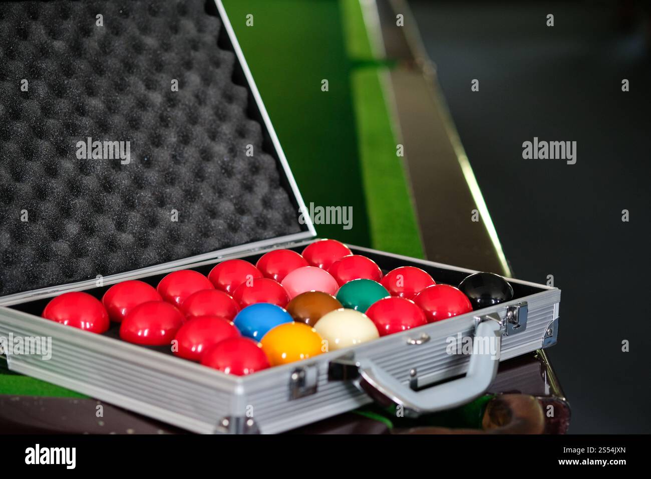 Mans mano e braccio cue giocano a biliardo o si preparano a sparare palle da biliardo su un tavolo da biliardo verde. Palline da biliardo colorate sul fregio verde Foto Stock