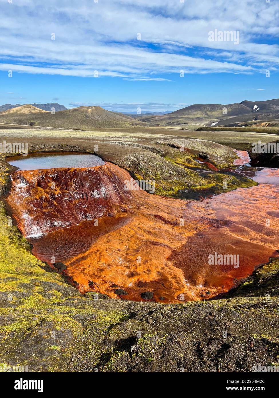 Veduta aerea di un fiume ricco di ferro rosso-arancio che si snoda attraverso le Highlands islandesi. Le sue forme astratte creano un paesaggio naturale surreale e vivace Foto Stock