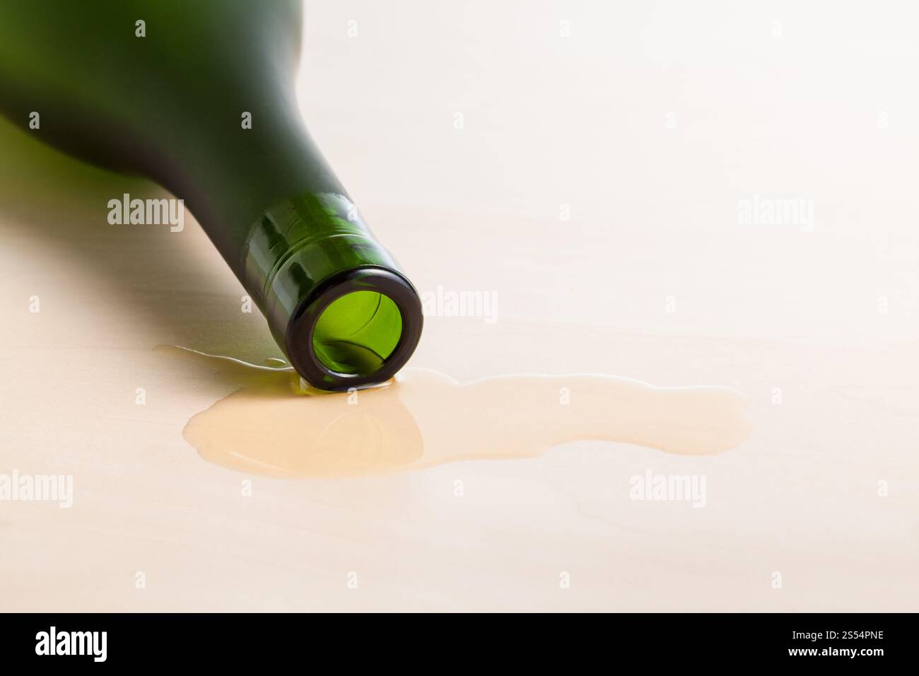 bordo del flacone di cognac in liquido versato su un tavolo di legno in primo piano. bordo del flacone di cognac nel liquido versato sul tavolo Foto Stock