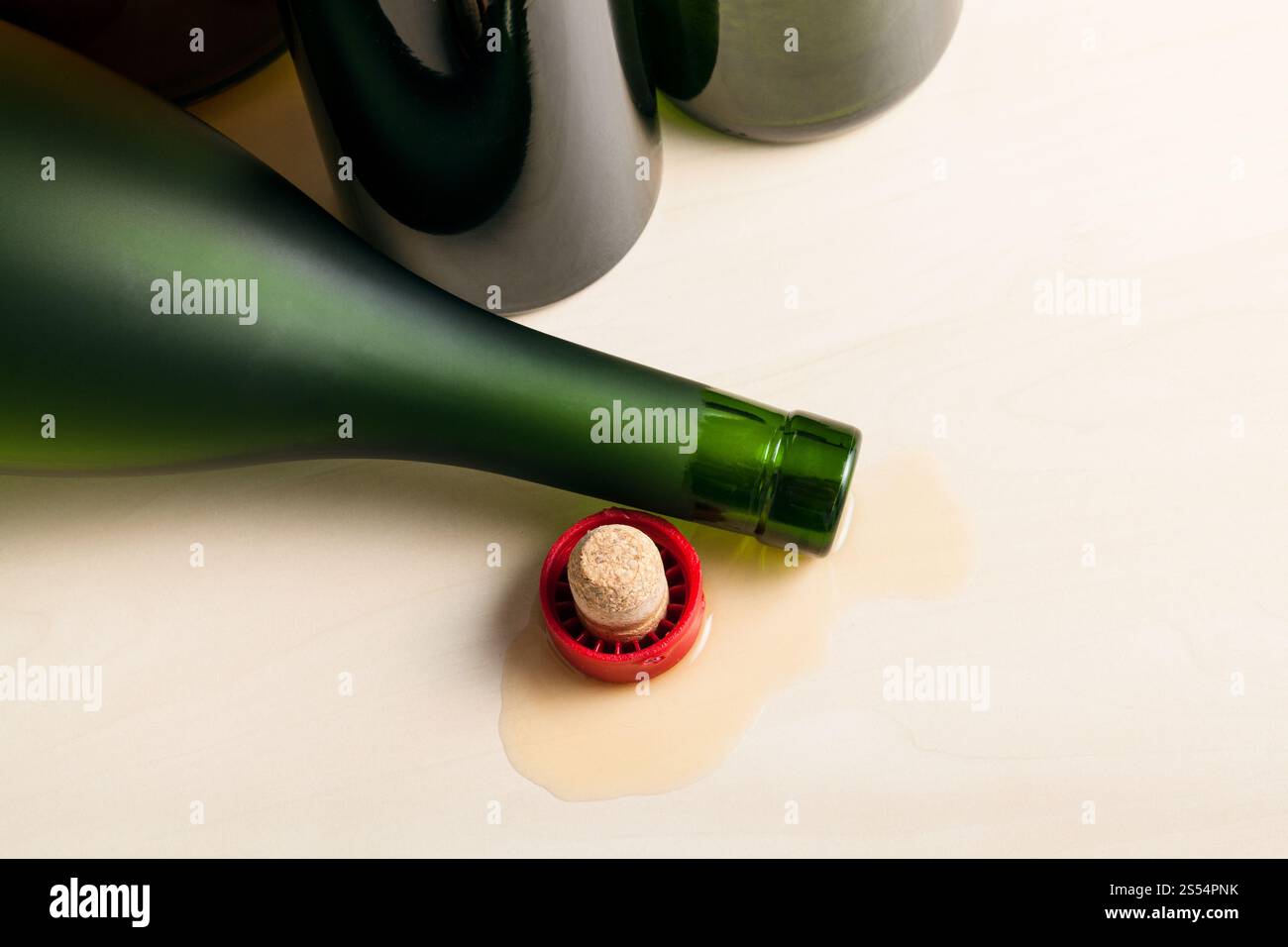 vista dall'alto della bottiglia di cognac rovesciata nel liquido versato vicino a bottiglie di vino vuote su un asse di legno. bottiglia in cognac fuoriuscito vicino a bottiglie di vino vuote Foto Stock