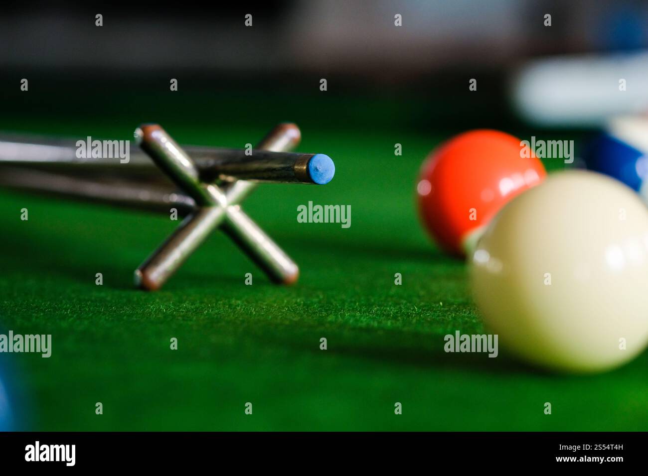 Mans mano e braccio cue giocano a biliardo o si preparano a sparare palle da biliardo su un tavolo da biliardo verde. Palline da biliardo colorate sul fregio verde Foto Stock