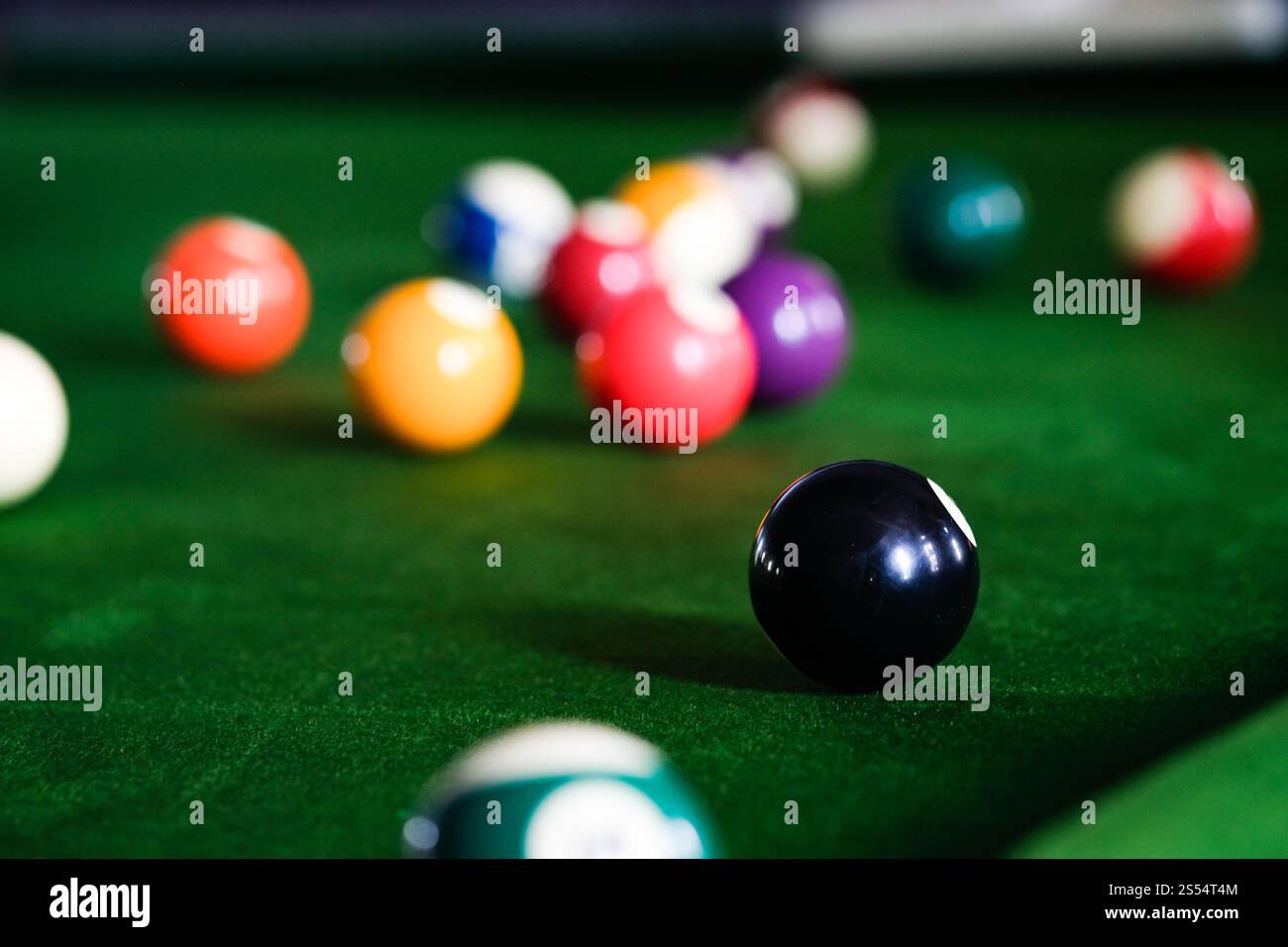 Mans mano e braccio cue giocano a biliardo o si preparano a sparare palle da biliardo su un tavolo da biliardo verde. Palline da biliardo colorate sul fregio verde Foto Stock