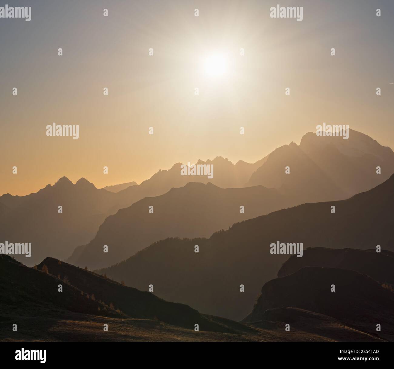 Il sole bagliore di sera, il cielo nebbioso e le sagome delle montagne. Vista tranquilla dal passo di Giau. Clima, ambiente e concetto di viaggio. Foto Stock