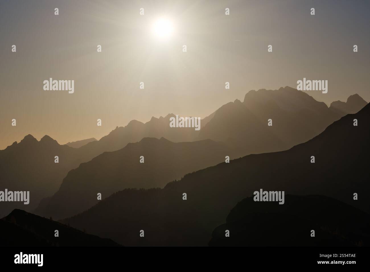 Il sole bagliore di sera, il cielo nebbioso e le sagome delle montagne. Vista tranquilla dal passo di Giau. Clima, ambiente e concetto di viaggio. Foto Stock