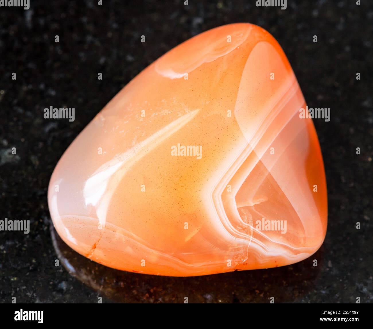 primo piano di un campione di minerale naturale proveniente dalla collezione geologica - roccia corneliana (corneliana) rovesciata su fondo di granito nero del Madagascar. Foto Stock