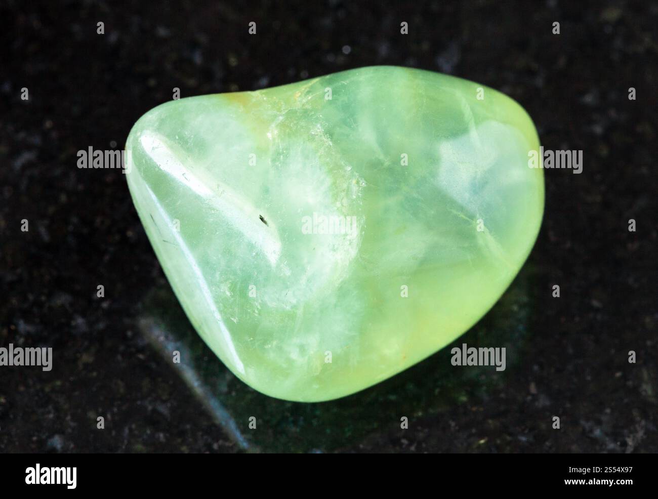 primo piano di un campione di minerale naturale proveniente dalla collezione geologica - roccia prehnite lucidata su fondo di granito nero proveniente dalla Repubblica del Mali. lucidato Foto Stock