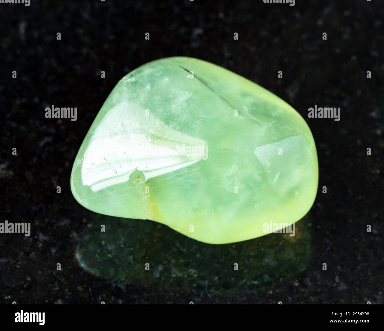 primo piano di un campione di minerale naturale proveniente dalla raccolta geologica - roccia di Prehnite tumulata su fondo di granito nero proveniente dalla Repubblica del Mali. rovesciato Foto Stock