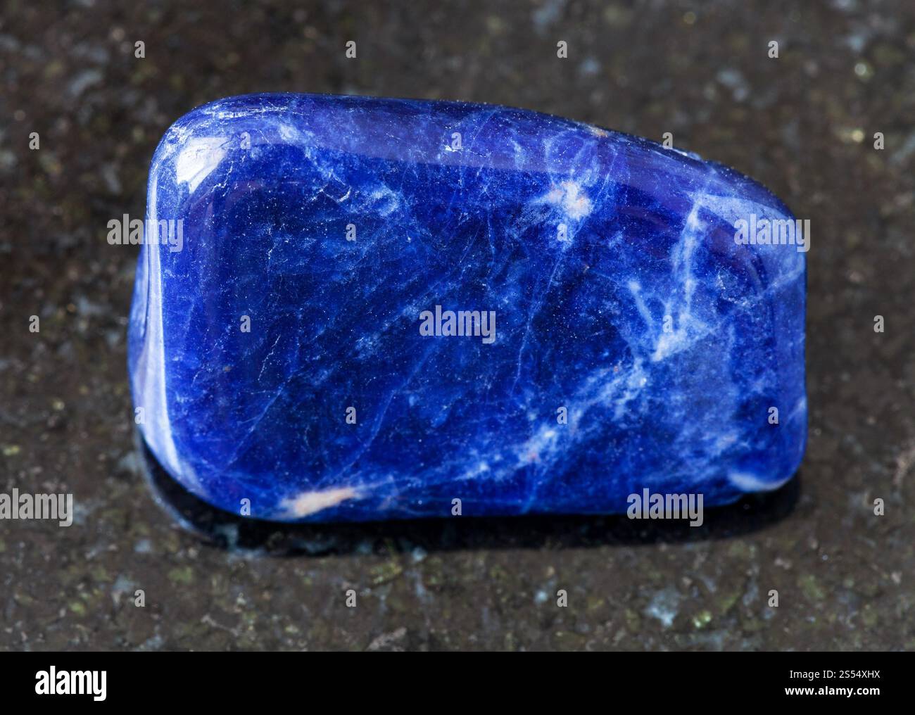 primo piano di un campione di minerale naturale proveniente dalla raccolta geologica - Sodalite tumulata su fondo di granito nero proveniente dal Brasile. Sodalite rovesciata Foto Stock