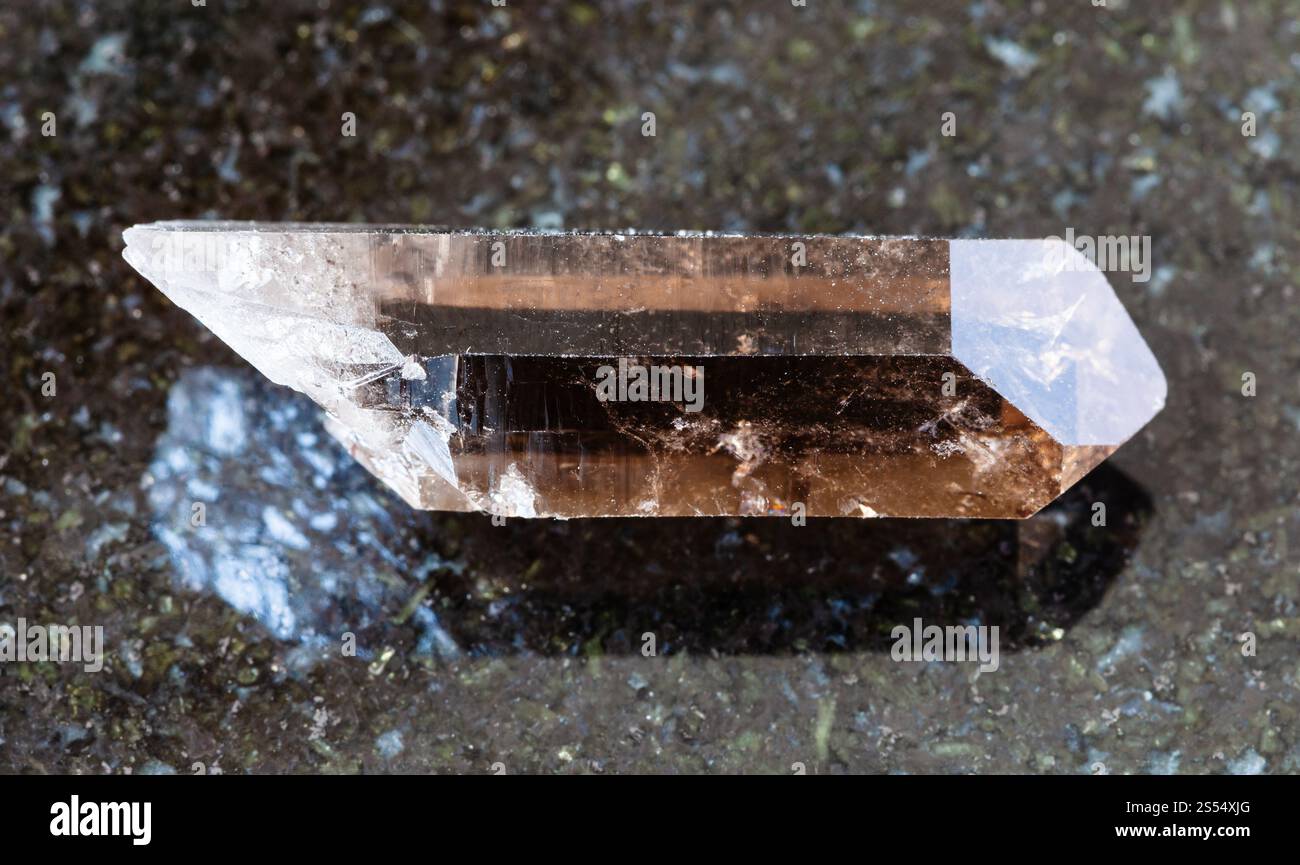primo piano del campione di minerale naturale proveniente dalla collezione geologica - cristallo non lucido di quarzo affumicato su fondo di granito nero proveniente da Pelinguichy, Foto Stock