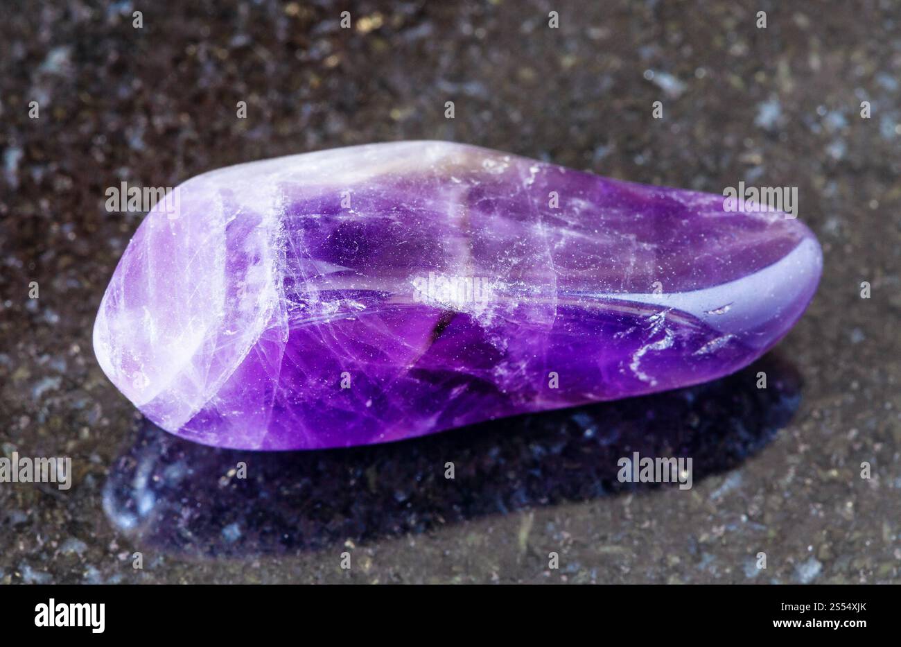 primo piano del campione di minerale naturale proveniente dalla raccolta geologica - roccia Ametista lucidata su fondo granitico nero della Namibia. Ametista lucidato Foto Stock