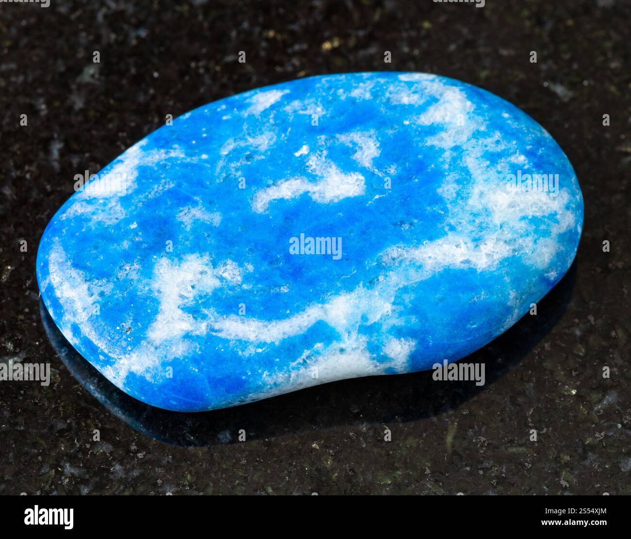 primo piano di un campione di minerale naturale proveniente dalla collezione geologica - roccia di Lazurite (Lapis Lazuli) tumulata su sfondo di granito nero proveniente dal Tagikistan. Foto Stock