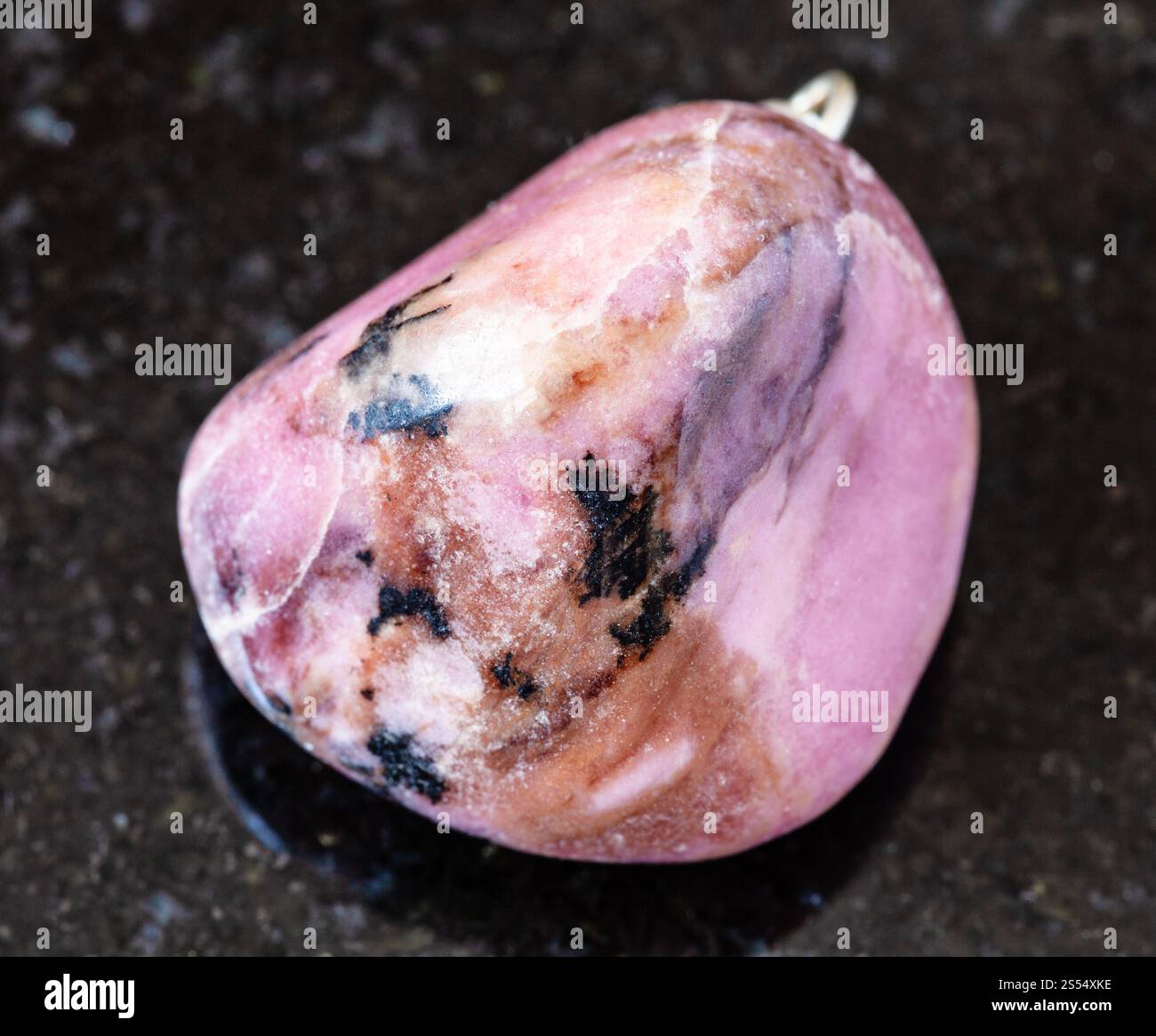 primo piano di un campione di minerale naturale proveniente dalla collezione geologica - rocce rodonite lucide su fondo di granito nero proveniente dal Tagikistan. lucidato Foto Stock