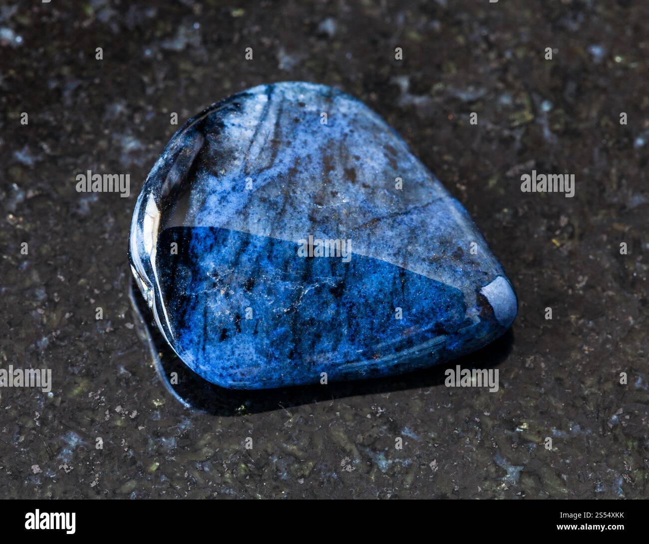 primo piano di un campione di minerale naturale proveniente dalla collezione geologica - roccia Dumortierite lucida su fondo di granito nero proveniente dal Mozambico. lucidato Foto Stock