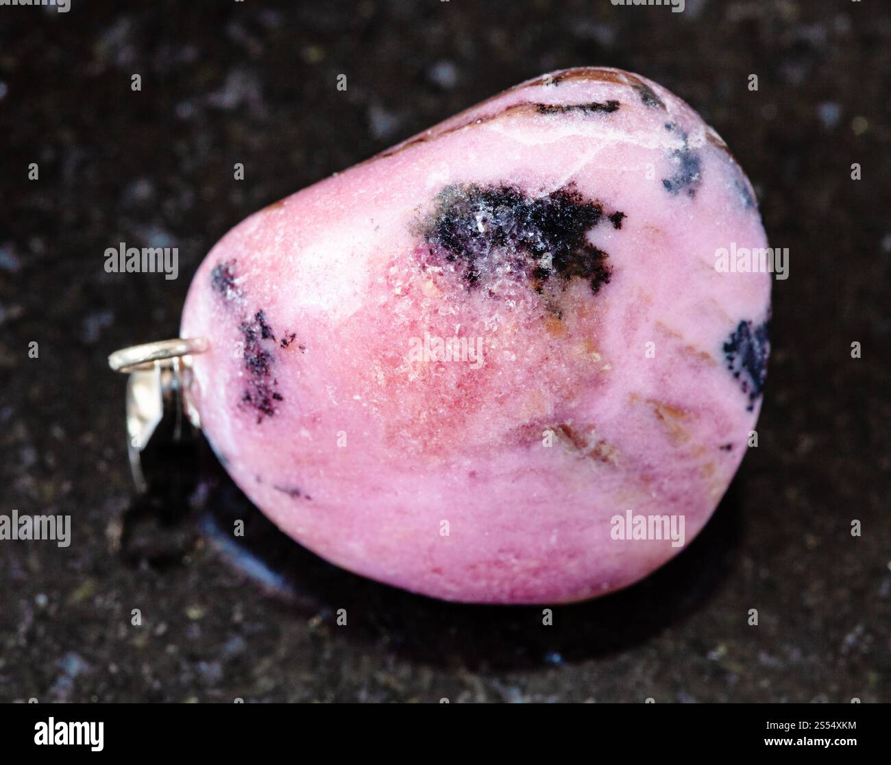 primo piano di un campione di minerale naturale proveniente dalla collezione geologica - roccia rodonita tumulata su fondo di granito nero proveniente dal Tagikistan. rovesciato Foto Stock