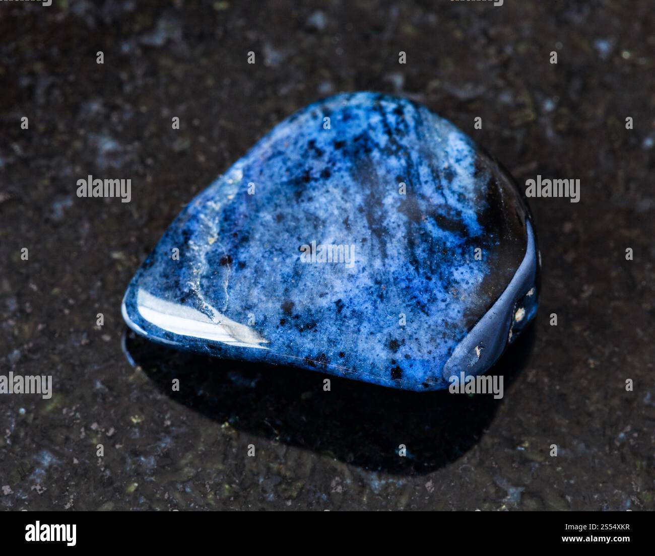 primo piano di un campione di minerale naturale proveniente dalla collezione geologica - roccia di Dumortierite laminata su fondo di granito nero proveniente dal Mozambico. arrotolato Foto Stock