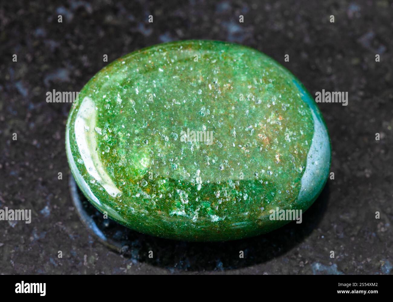 primo piano di un campione di minerale naturale proveniente dalla collezione geologica - pietra verde lucidata di Aventurine su fondo di granito nero proveniente dall'India. Foto Stock