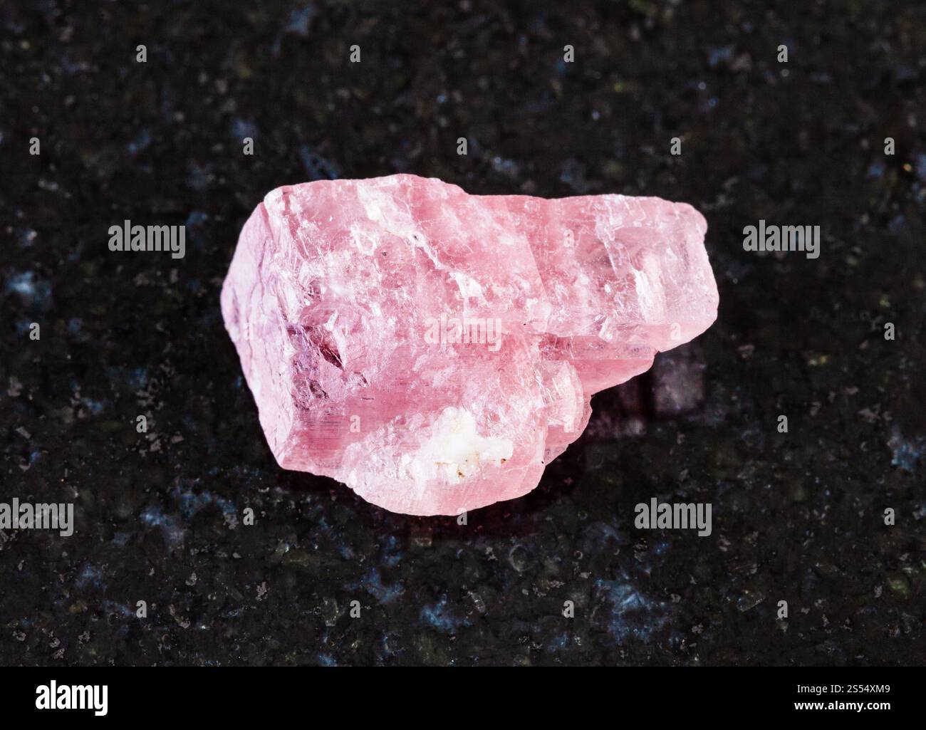 primo piano del campione di minerale naturale proveniente dalla raccolta geologica - cristallo rodocrosito non lucidato su fondo granitico nero proveniente dalla miniera di Wutong, Foto Stock