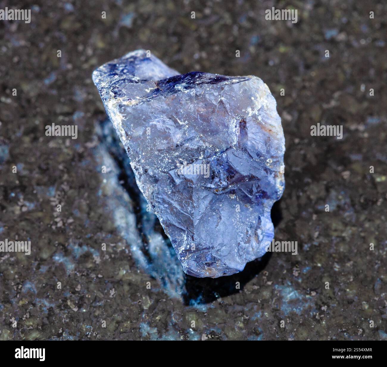 primo piano di un campione di minerale naturale proveniente dalla collezione geologica - cristallo di Cordierite (Iolite) non lucidato su fondo di granito nero del Madagascar. Foto Stock