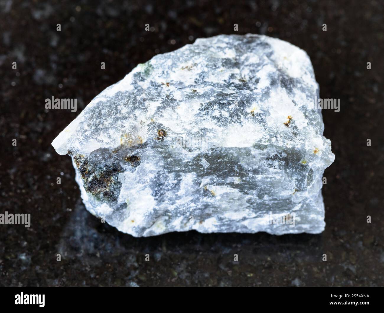 primo piano di un campione di minerale naturale proveniente dalla collezione geologica - roccia di Melilitolite non lucidata su fondo di granito nero. Melilitolite non lucida Foto Stock