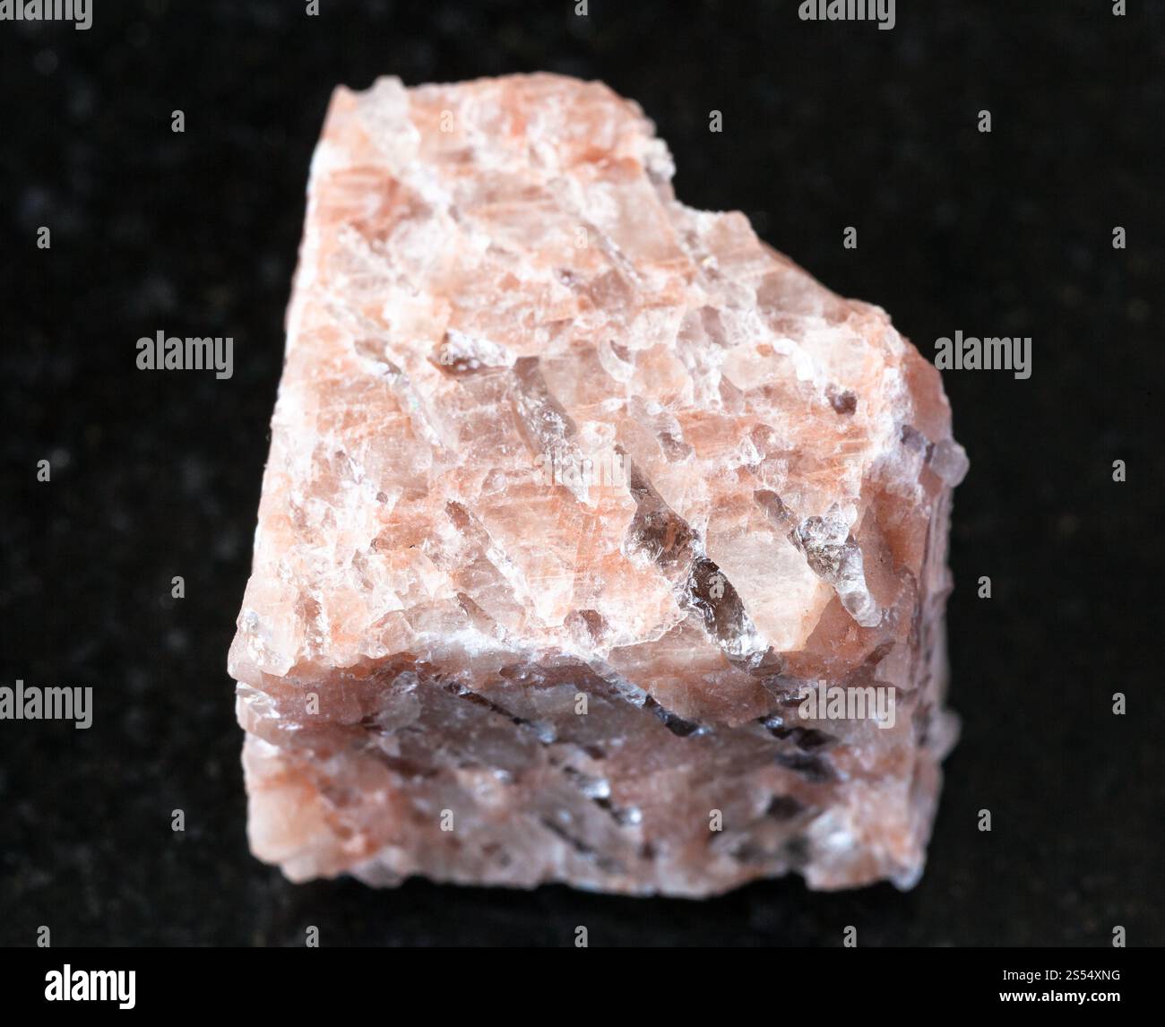 primo piano di un campione di minerale naturale proveniente dalla raccolta geologica - roccia grezza di granito Pegmatite su fondo di granito nero. Pegmatite di granito ruvido Foto Stock